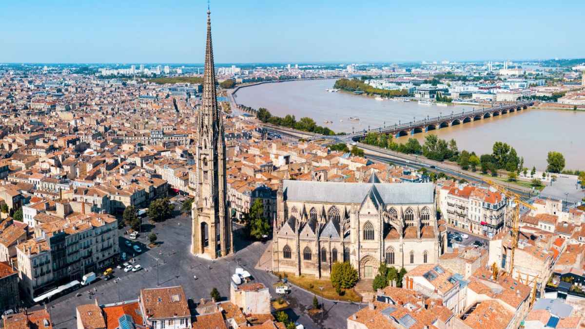 Vista aérea de una ciudad europea con catedral gótica y río, relacionada con ofertas de empleo para españoles