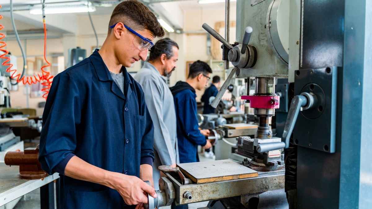 Estudiantes de FP realizando prácticas en un taller industrial con maquinaria durante su formación profesional.