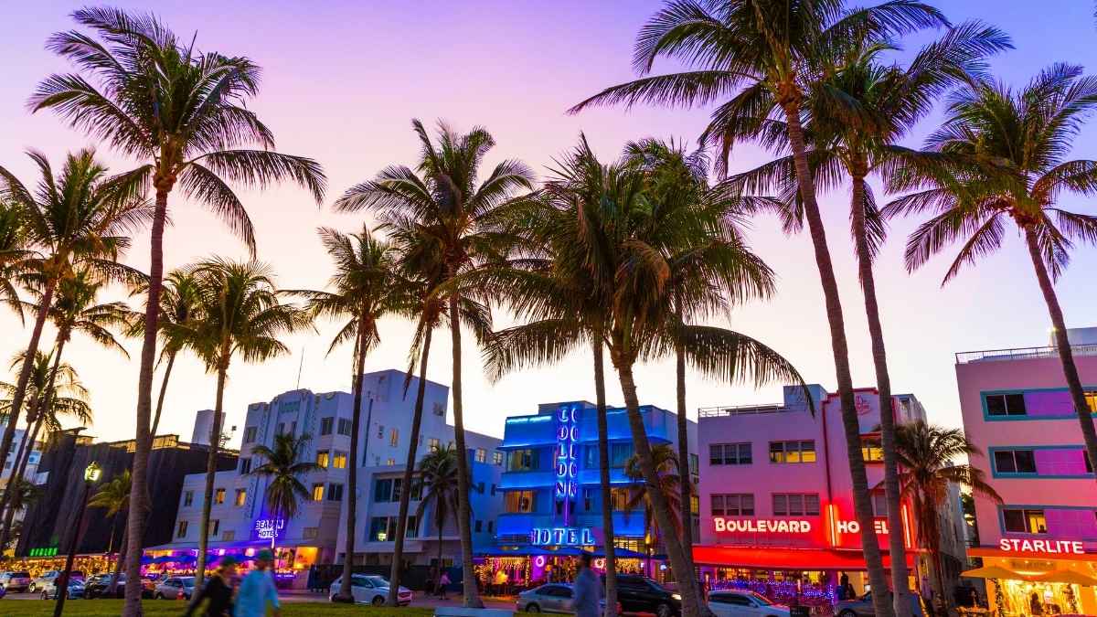 Vista de Ocean Drive en Miami con hoteles iluminados y palmeras al atardecer