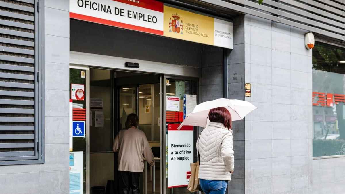 Personas entrando a una oficina de empleo del SEPE en un día de lluvia
