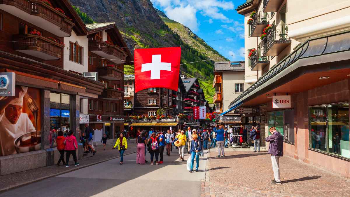 Calle comercial de una ciudad suiza con bandera de Suiza y turistas paseando