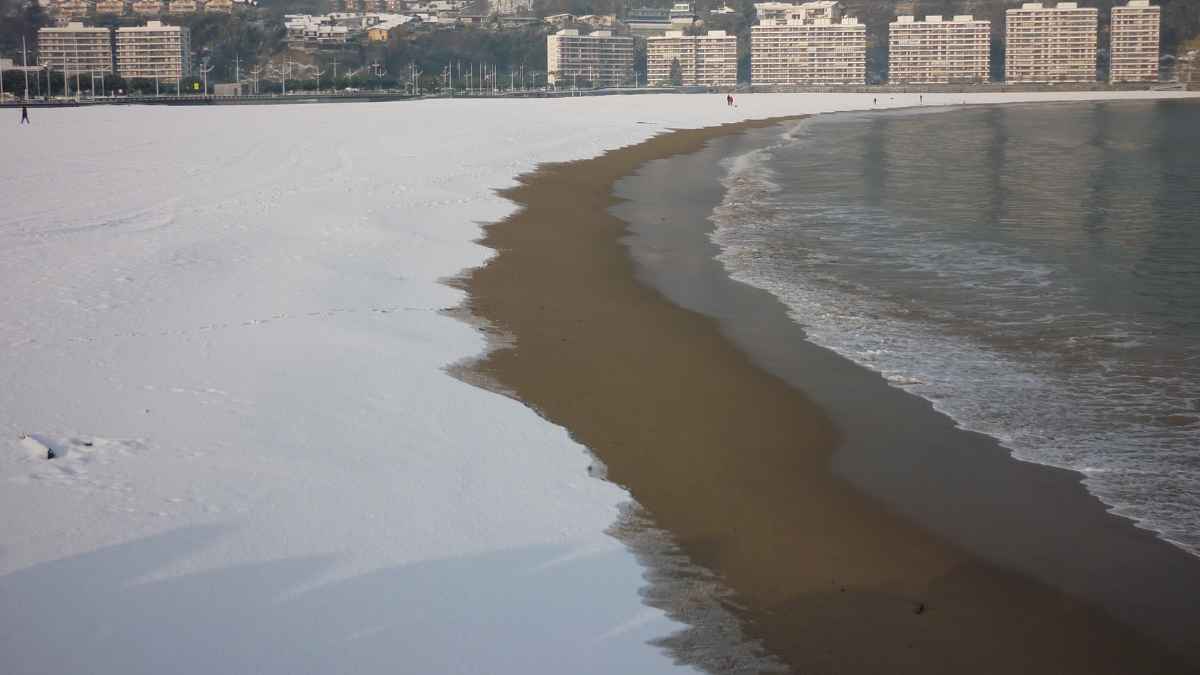 Playa cubierta de nieve junto al mar durante un episodio invernal con frío y avisos de AEMET