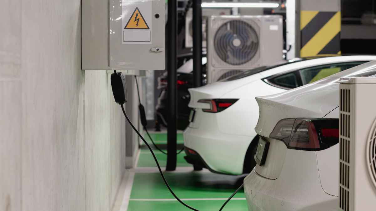 Coche eléctrico cargando en un garaje comunitario con punto de recarga instalado en la pared