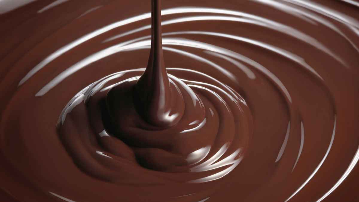 Chocolate espeso vertiéndose con textura perfecta para acompañar churros