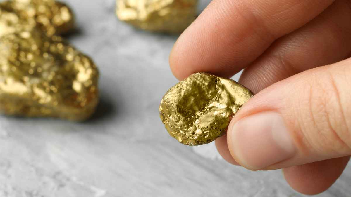 Pepita de oro en primer plano sostenida con la mano representando el hallazgo del yacimiento gigante descubierto en China