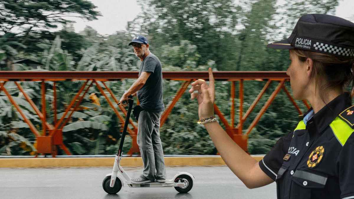 Agente de policia señala a un conductor de patinete electrico por nuevas sanciones de la dgt desde 2026