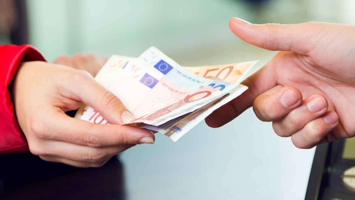 Persona entregando billetes de euro en un pago en efectivo en un comercio.
