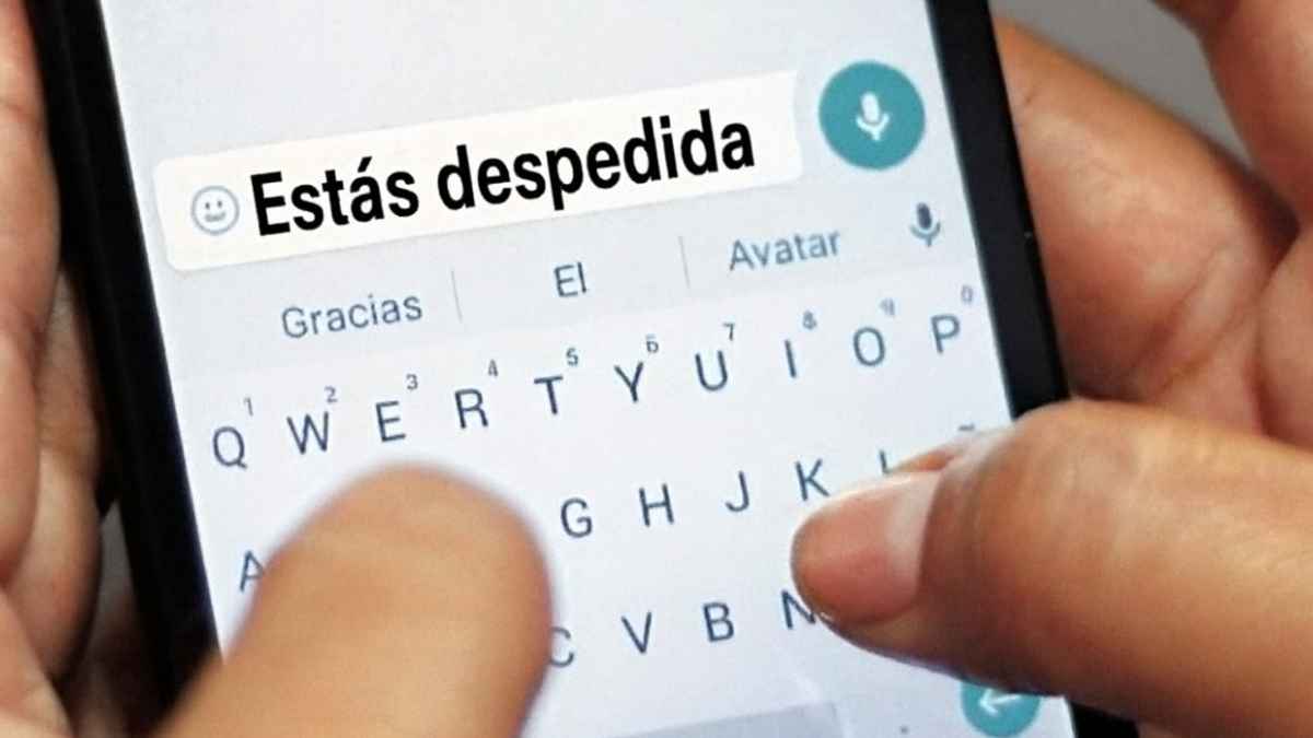 Manos escribiendo un mensaje de WhatsApp en un móvil informando del despido.