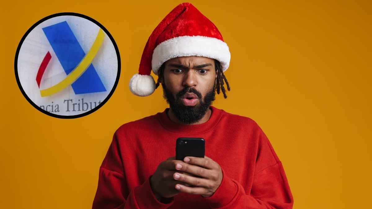 Hombre sorprendido consultando el móvil con gorro de Navidad junto al logotipo de la Agencia Tributaria