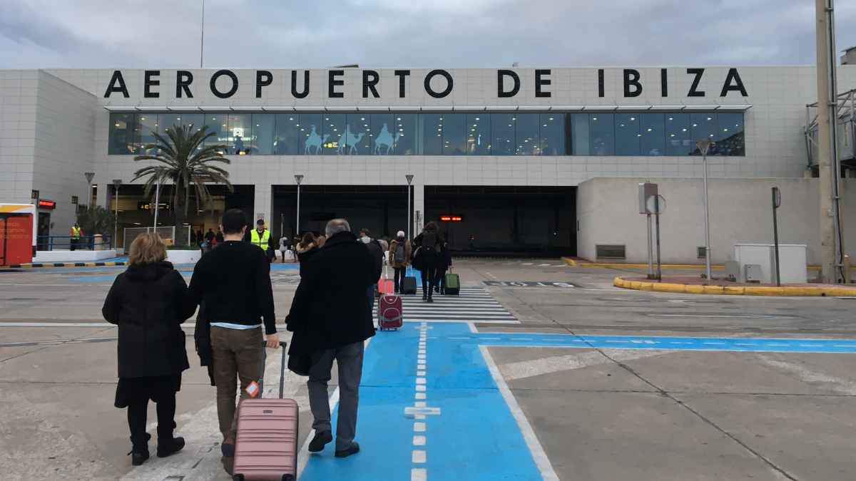 Personas acceden al Aeropuerto de Ibiza con maletas en una mañana laboral