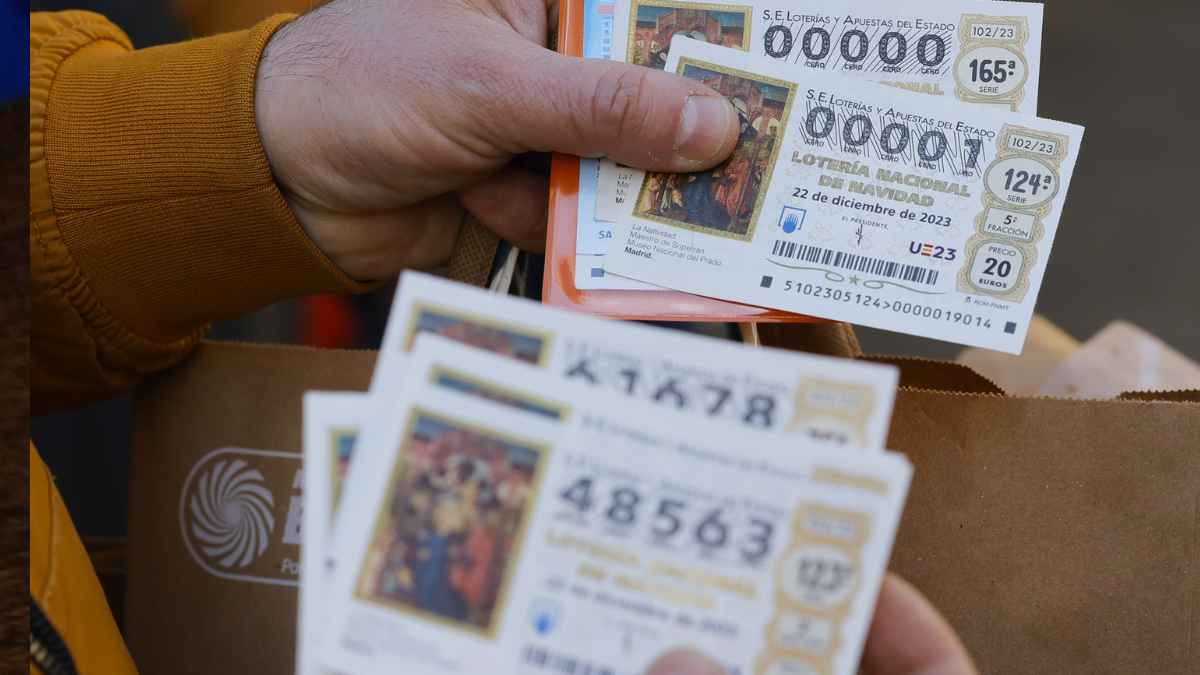 Persona sosteniendo varios décimos de la Lotería de Navidad mientras muestra boletos oficiales en una compra
