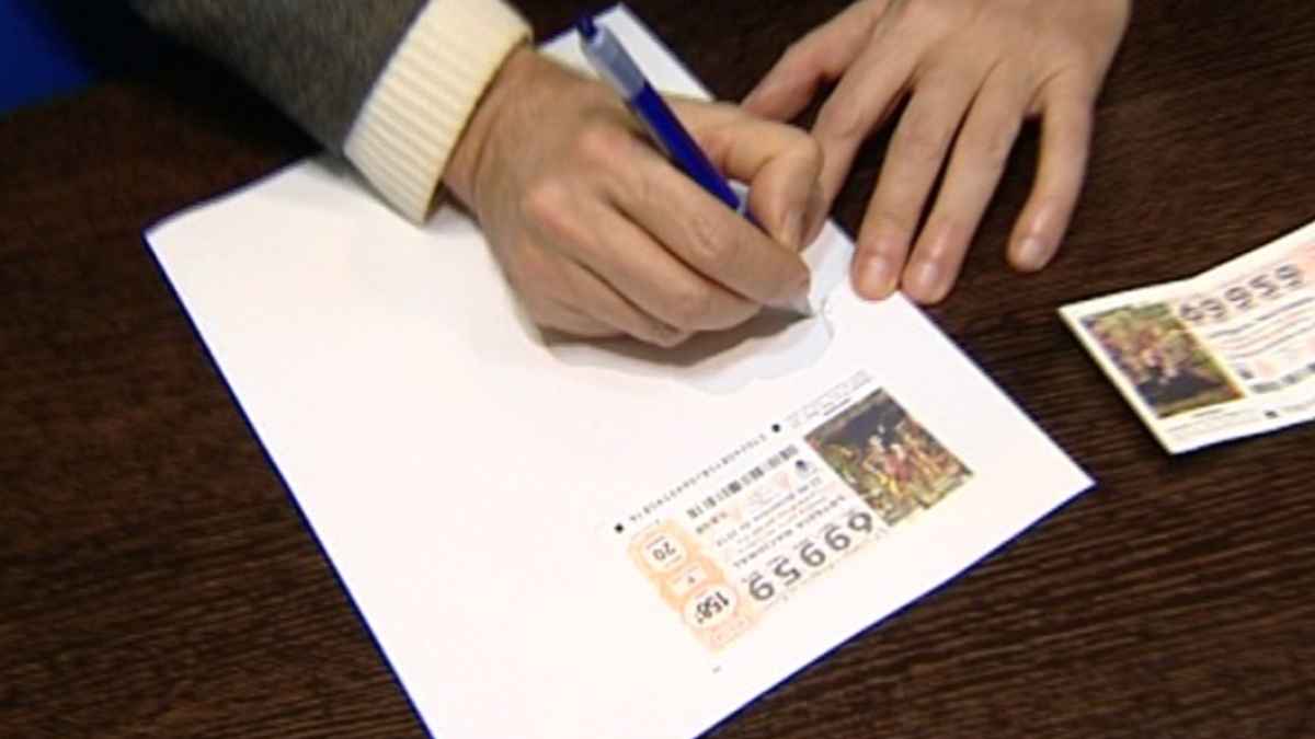 persona rellenando un documento junto a un décimo de la lotería de navidad para acreditar un premio compartido