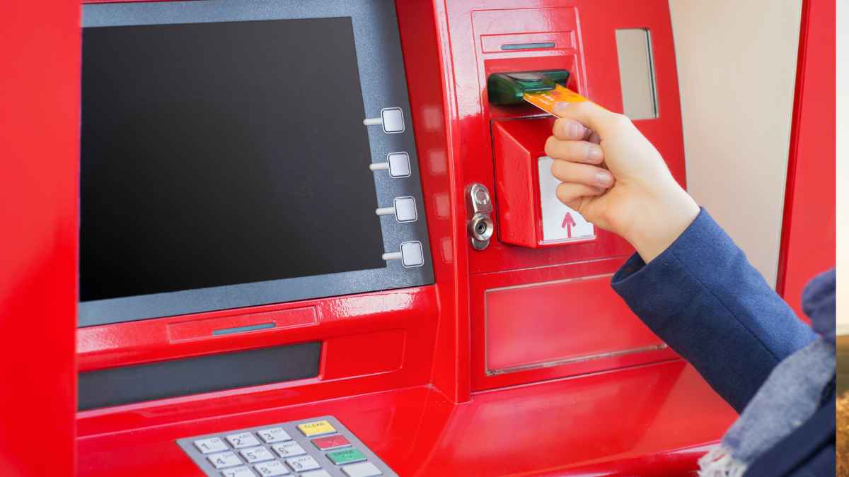 Persona introduciendo una tarjeta bancaria en un cajero automático rojo