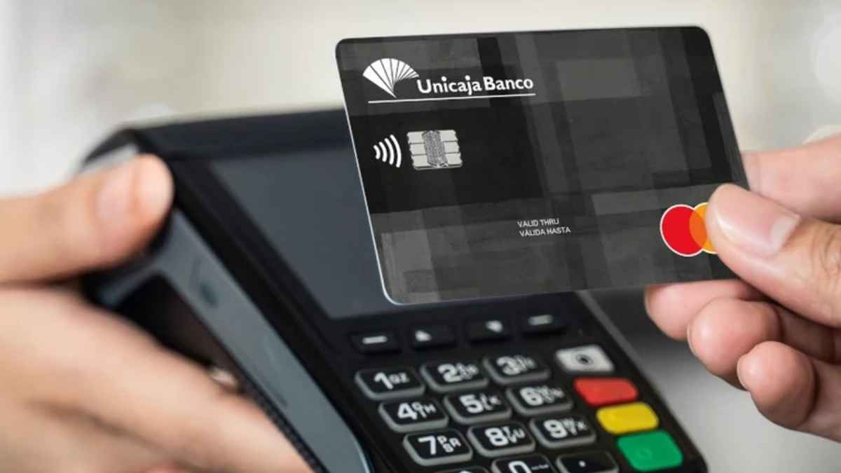 una persona pagando con una tarjeta de Unicaja en un terminal TPV con tecnología contactless