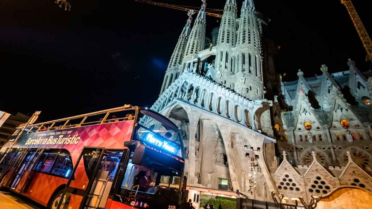 Autobús turístico en Barcelona frente a la Sagrada Familia iluminada por la noche