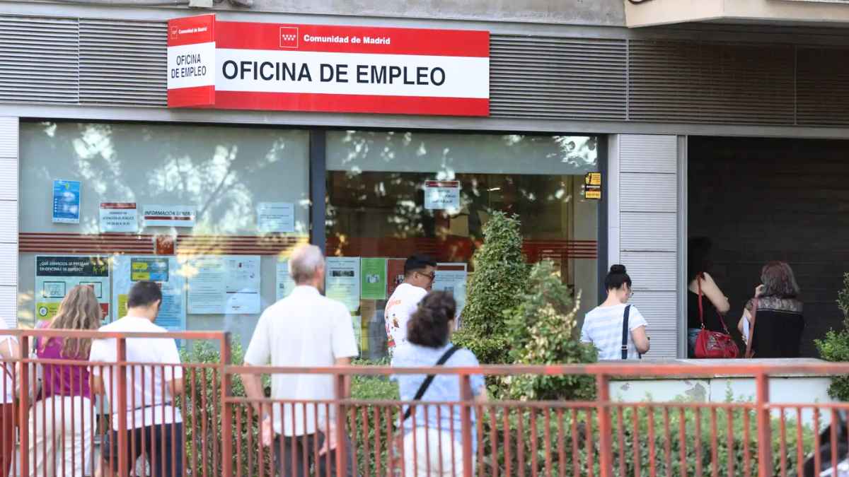 Personas esperando en una oficina de empleo mientras la justicia reconoce el derecho de una mujer a cobrar el subsidio tras años cuidando de sus hijas