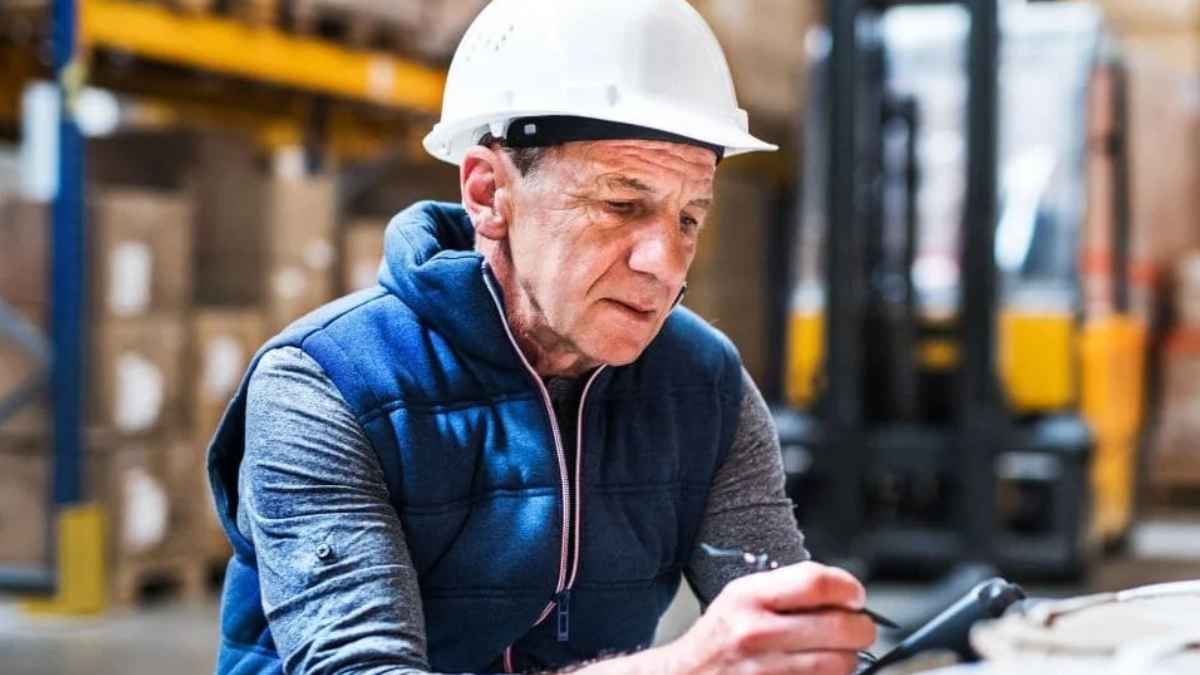 Trabajador de edad avanzada con casco revisando documentación en su puesto de trabajo antes de la jubilación