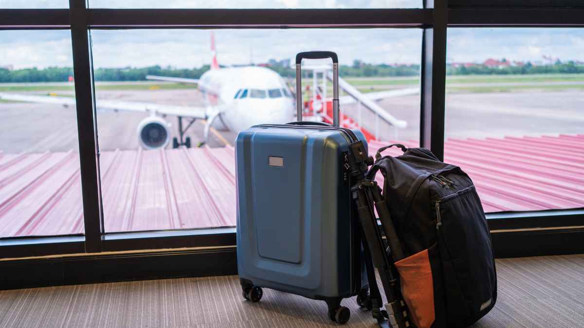 Maleta de cabina y mochila junto a un avión en un aeropuerto, imagen sobre las nuevas normas del equipaje de mano en la UE en 2026