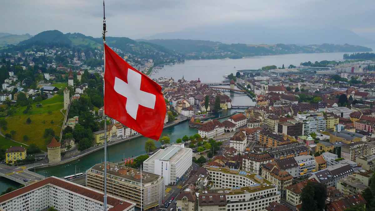Bandera de Suiza sobre una ciudad junto a un lago, imagen para una noticia sobre la multa de 107 euros por cruzar un pueblo en menos de 15 minutos usando el GPS