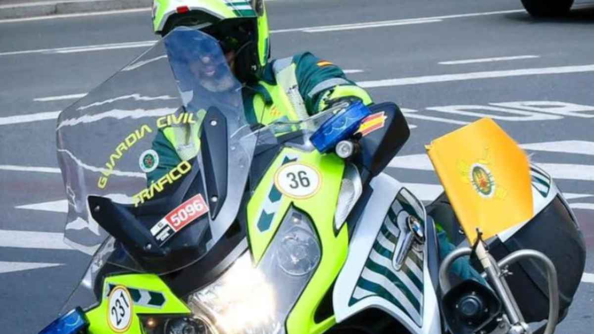 Guardia Civil de Tráfico en moto señalizando con una bandera amarilla en la carretera