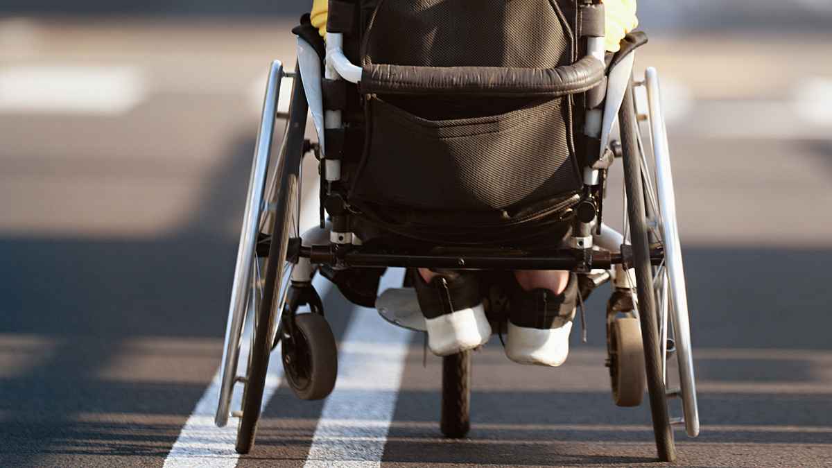 Persona en silla de ruedas cruzando una línea en la calle, reflejando la importancia de las limitaciones físicas en el contexto de la incapacidad permanente.