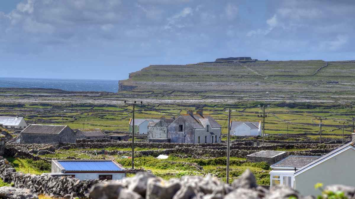 Paisaje rural en una isla de Irlanda con casas, muros de piedra y el mar al fondo