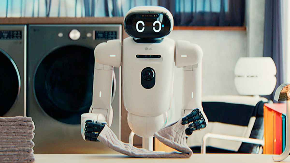 Robot doméstico CLOiD de LG doblando ropa sobre una mesa, con lavadora y ropa apilada al fondo.