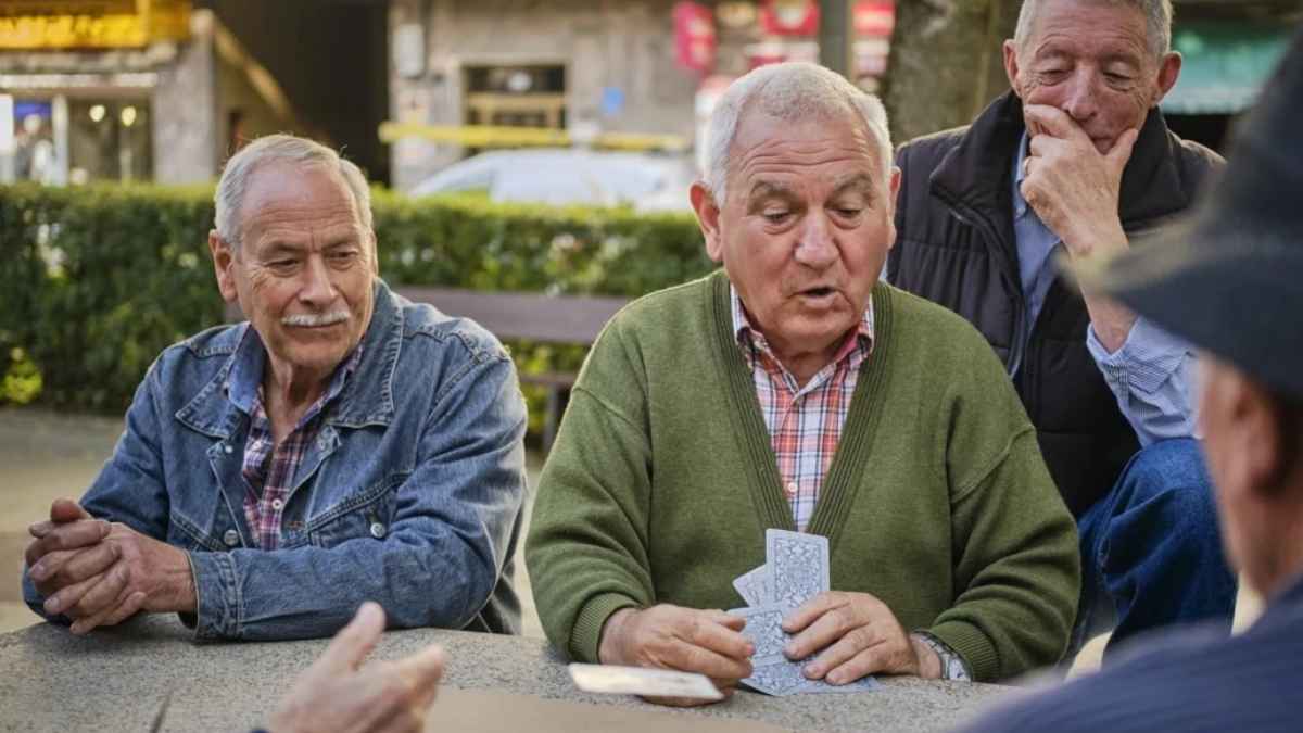 Jubilados mayores jugando a las cartas en un parque, imagen representativa de pensionistas que pueden recibir ayuda económica