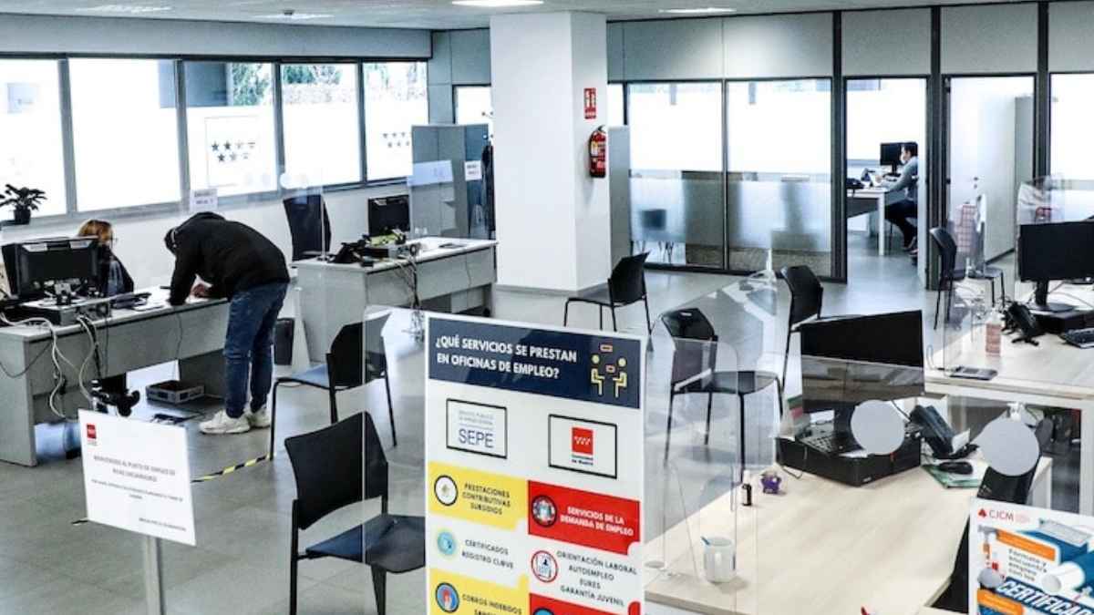 Oficina de empleo con puestos de atención al público y cartelería del SEPE relacionada con prestaciones y servicios.