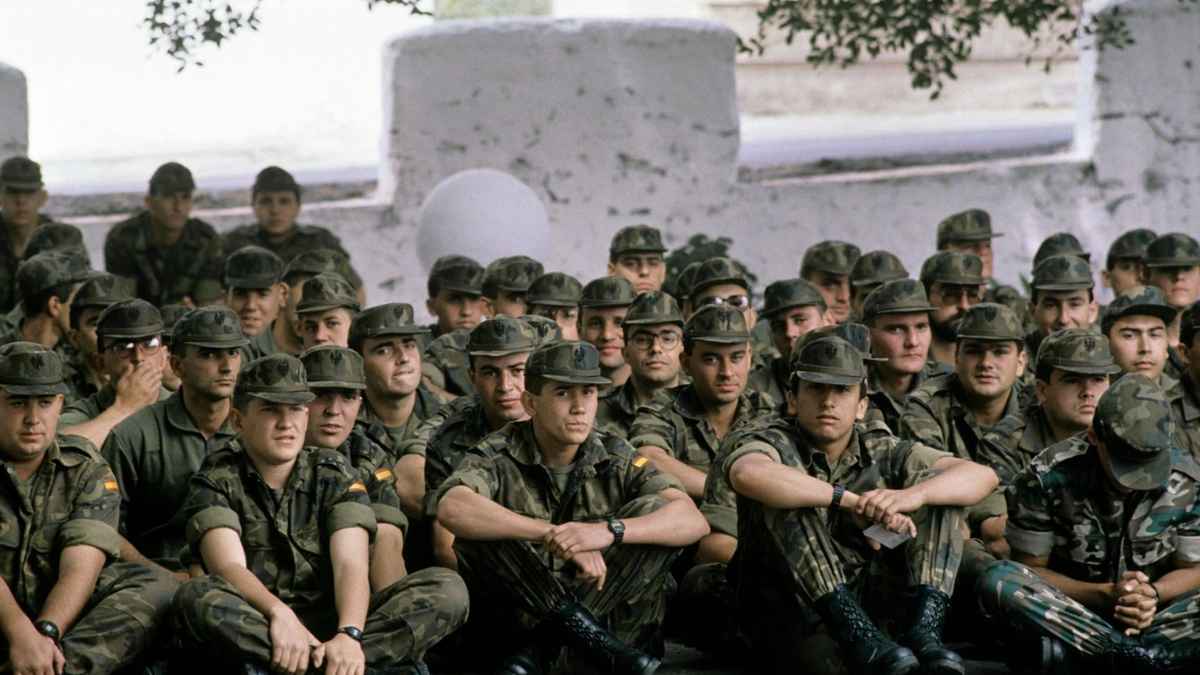 Reclutas del servicio militar obligatorio en España sentados con uniforme en una base militar durante los años 90