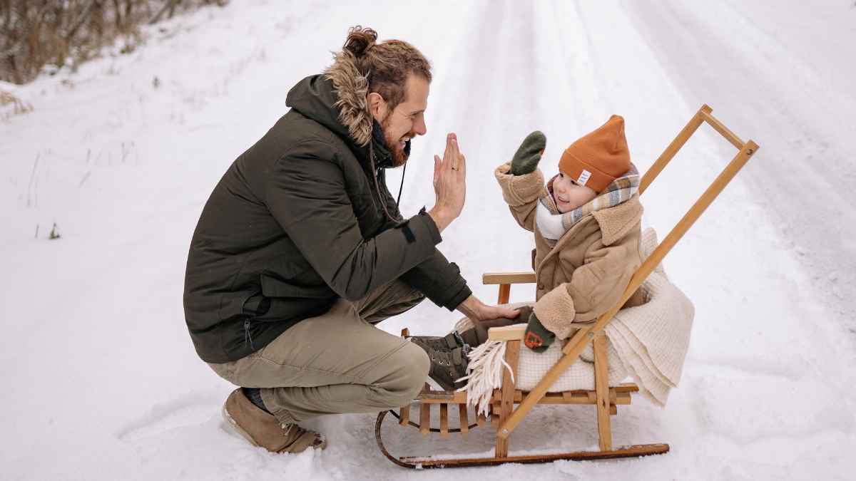 Padre chocando la mano con su hijo en la nieve, imagen del Día del Padre 2026 y el festivo del 19 de marzo