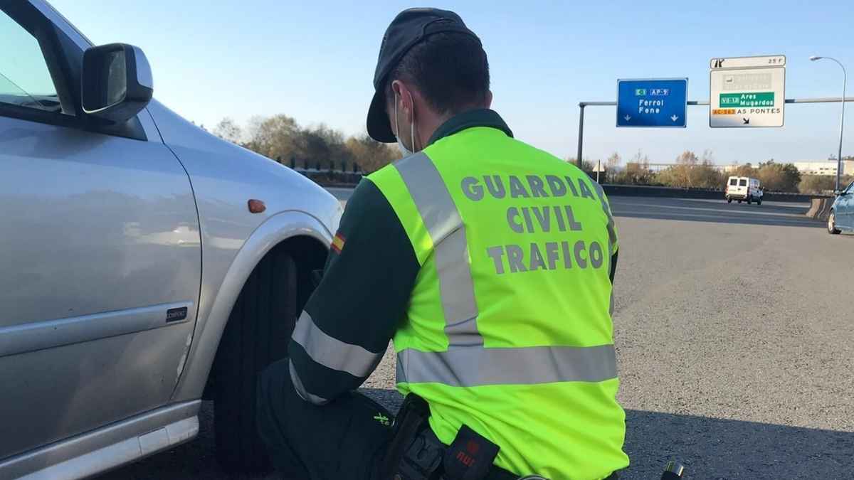 Agente de la Guardia Civil de Tráfico revisando el neumático de un coche en un control en carretera