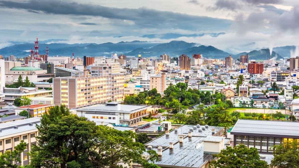 Vista panorámica de una ciudad japonesa con edificios y montañas al fondo, representando las zonas donde se venden casas a precios bajos en Japón debido al envejecimiento de la población