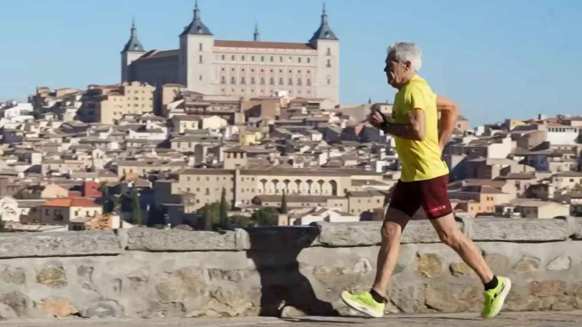 Hombre de 82 años corriendo al aire libre con la ciudad al fondo durante un entrenamiento