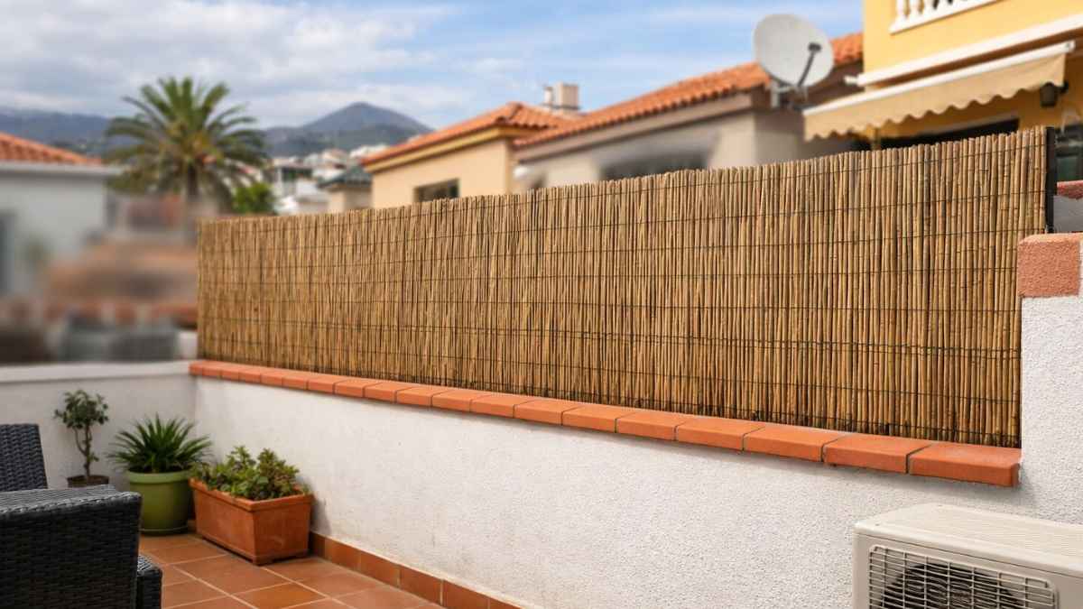 Cañizo instalado sobre murete interior de separación entre vecinos en una terraza de vivienda, sin afectar a la fachada.