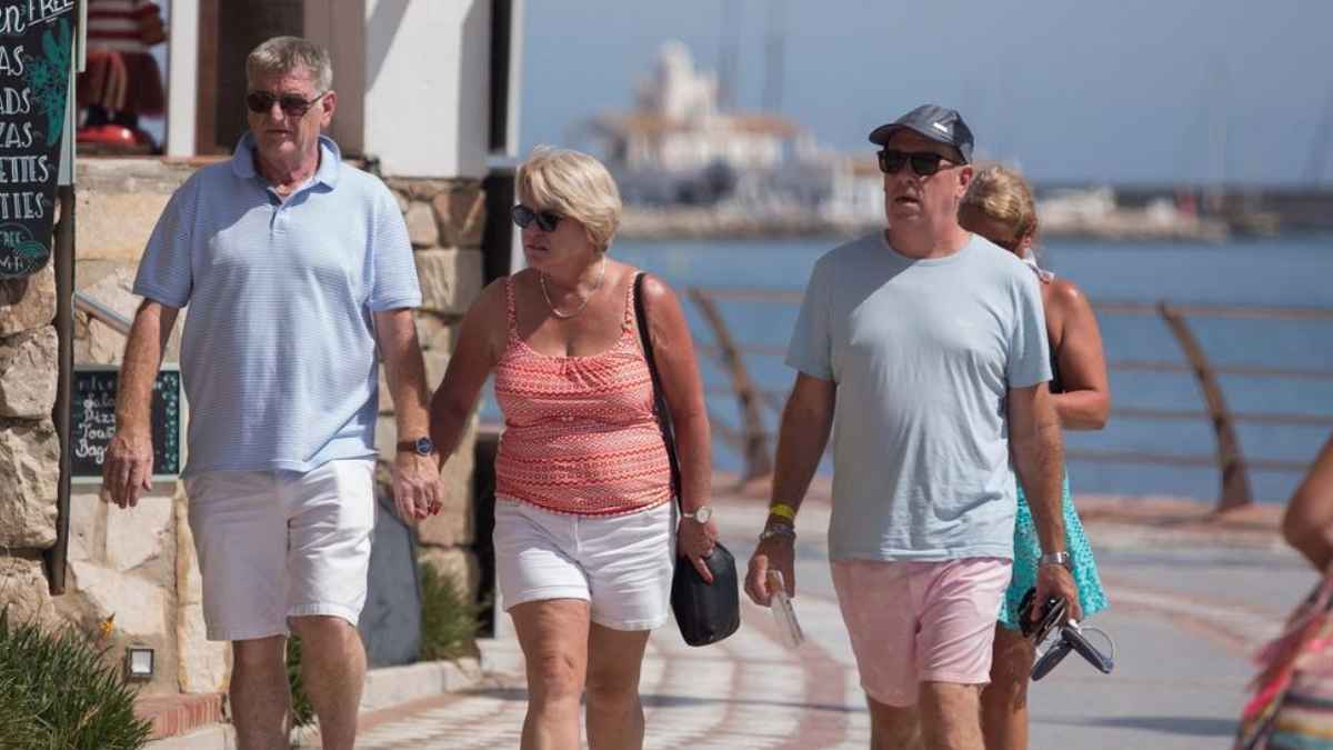 Personas mayores paseando por un paseo marítimo en España junto al mar