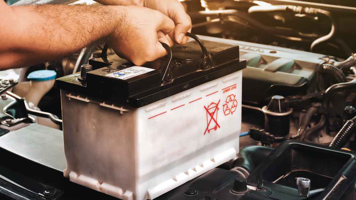 Manos manipulando una batería de coche para su sustitución y reciclaje