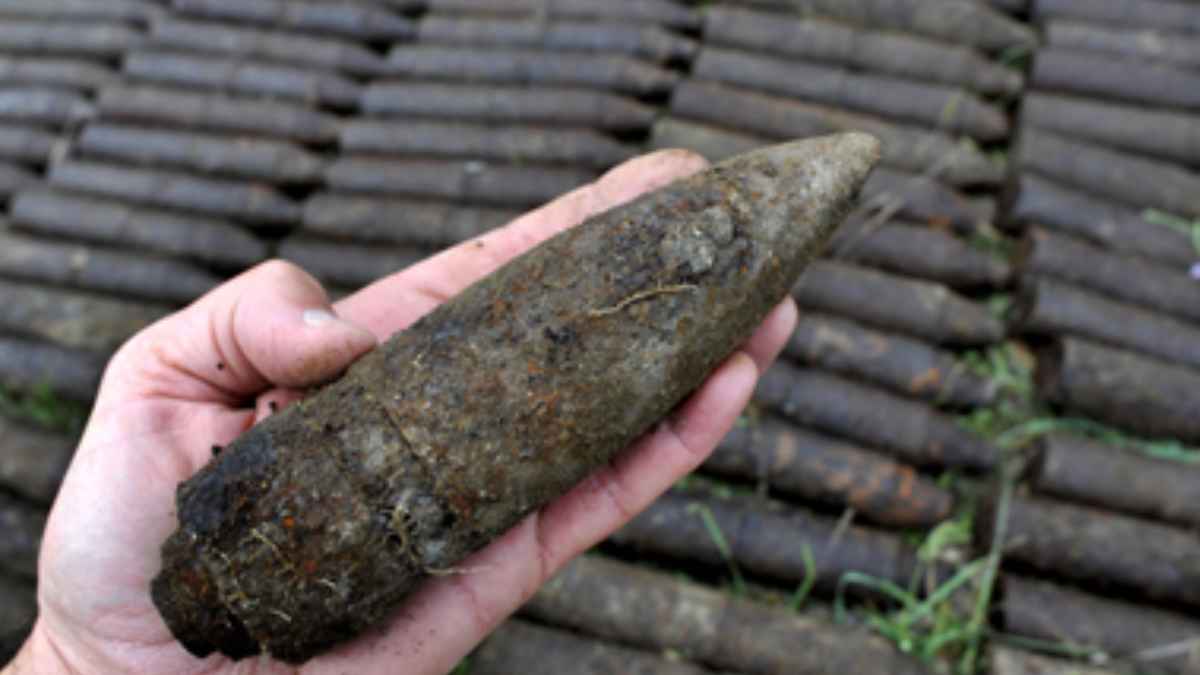 Mano sosteniendo un proyectil oxidado de la Guerra Civil tipo Huevo Kinder hallado en la playa de San Lorenzo junto al río Piles en Gijón