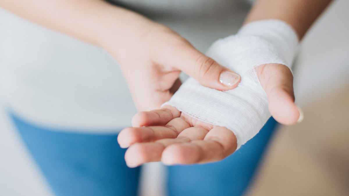 Persona con la mano vendada en baja laboral por incapacidad temporal de más de 18 meses