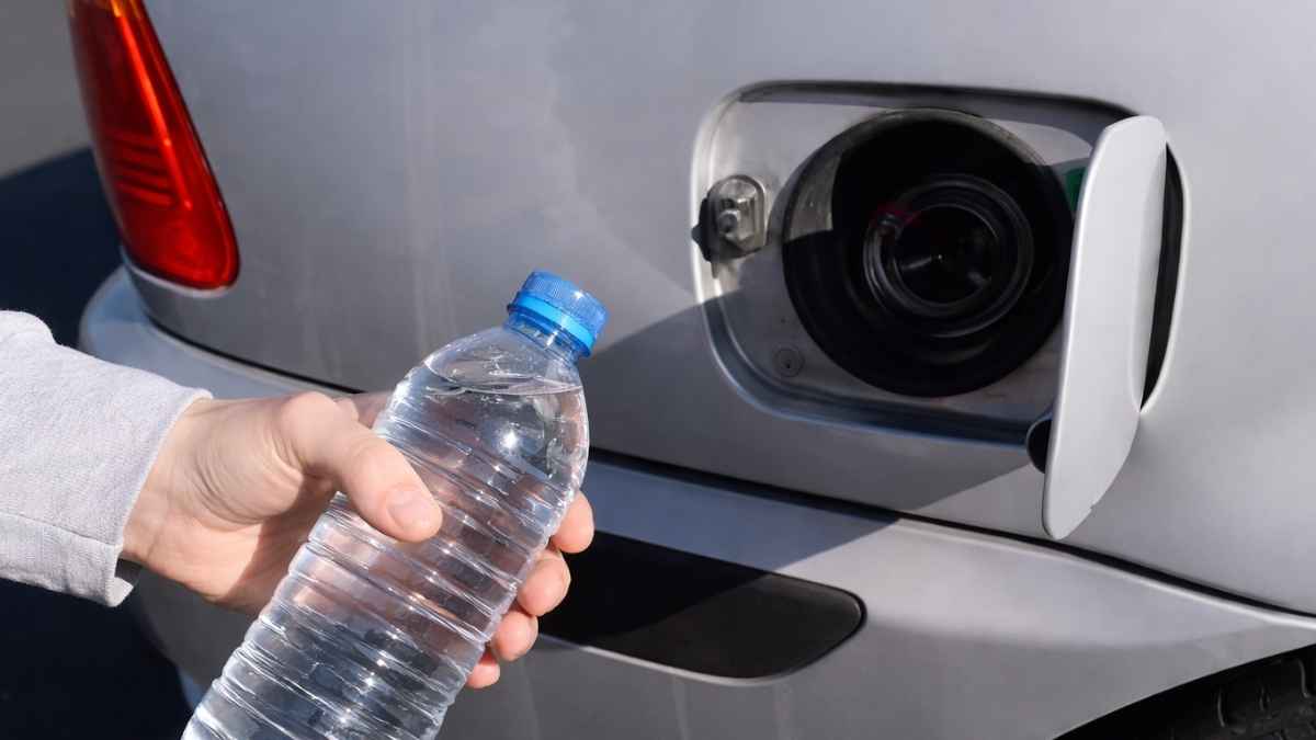 Botella de agua junto al depósito abierto de un coche diésel para ilustrar la mezcla agua-diésel