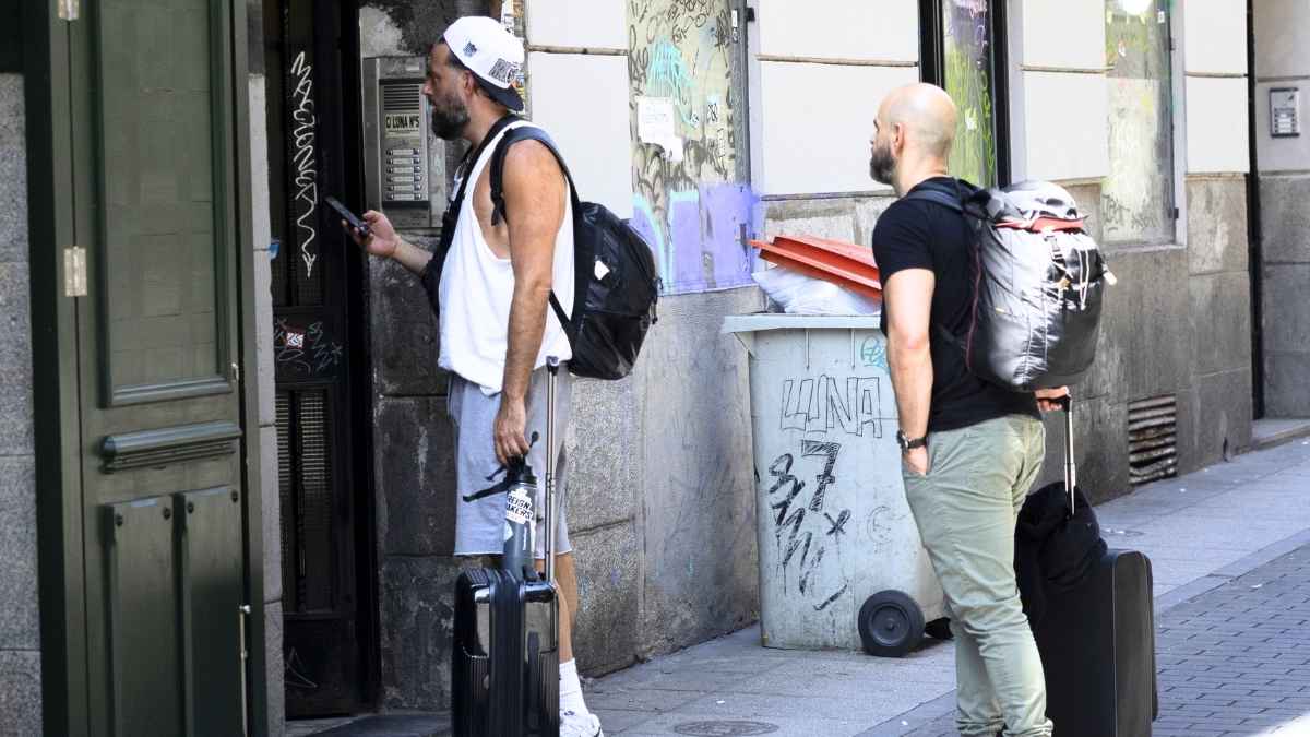 Dos viajeros con maletas entran en un edificio con piso turístico mientras la comunidad puede subir la cuota según la Ley de Propiedad Horizontal
