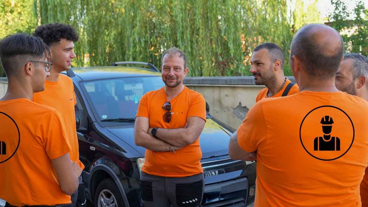 Trabajadores con camisetas naranjas hablando en grupo durante una pausa, relacionado con el descanso de 60 horas según el convenio