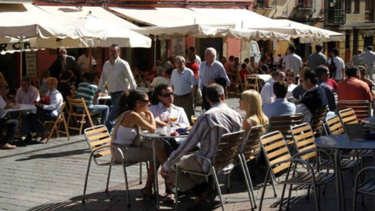 Grupo de personas en una terraza de bar durante el día, con varias mesas ocupadas en una zona al aire libre, ilustrando el tema de las salidas laborales a bares