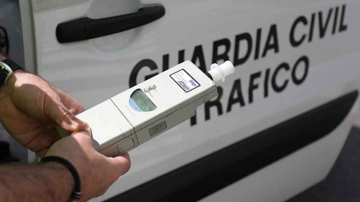 Agente con un etilómetro durante un control de alcoholemia junto a un vehículo de la Guardia Civil de Tráfico