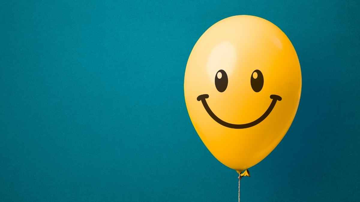 Globo amarillo con una cara sonriente sobre fondo azul, símbolo de felicidad y bienestar