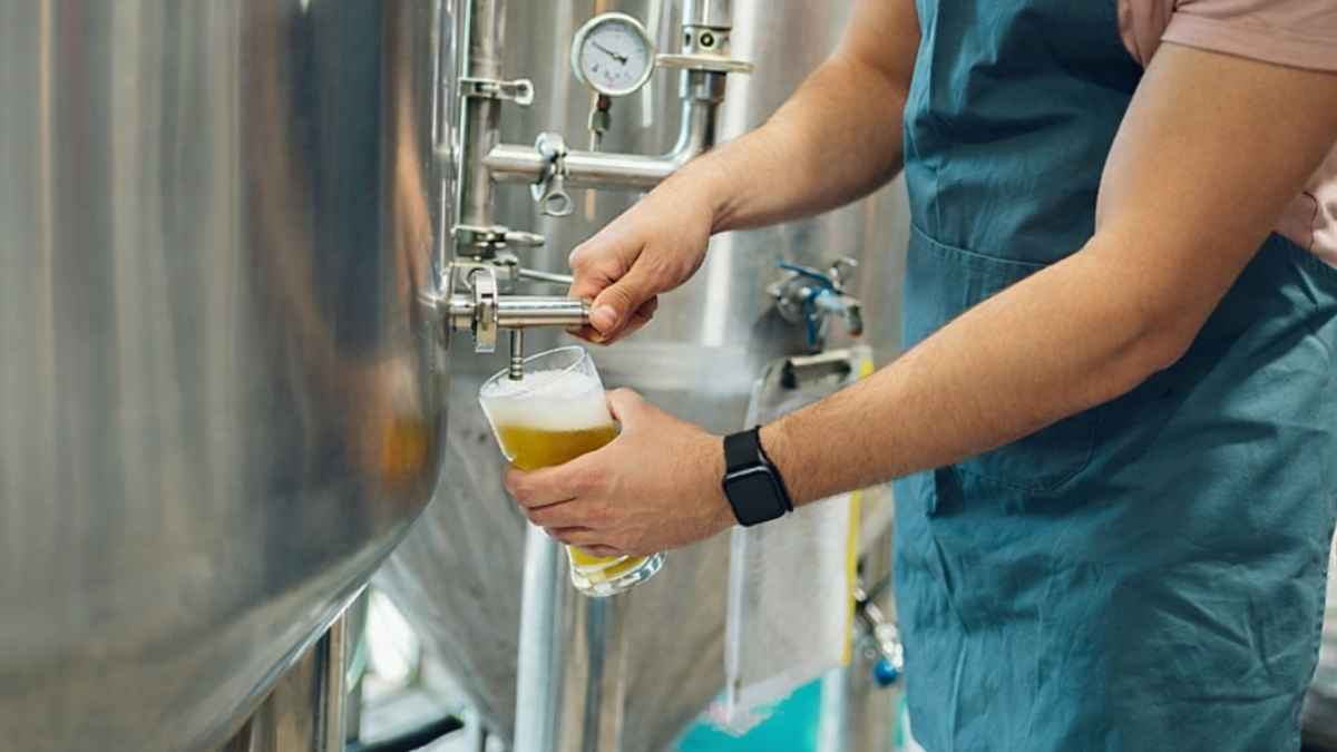 Persona sirviendo cerveza artesanal desde un tanque de acero inoxidable en una fábrica