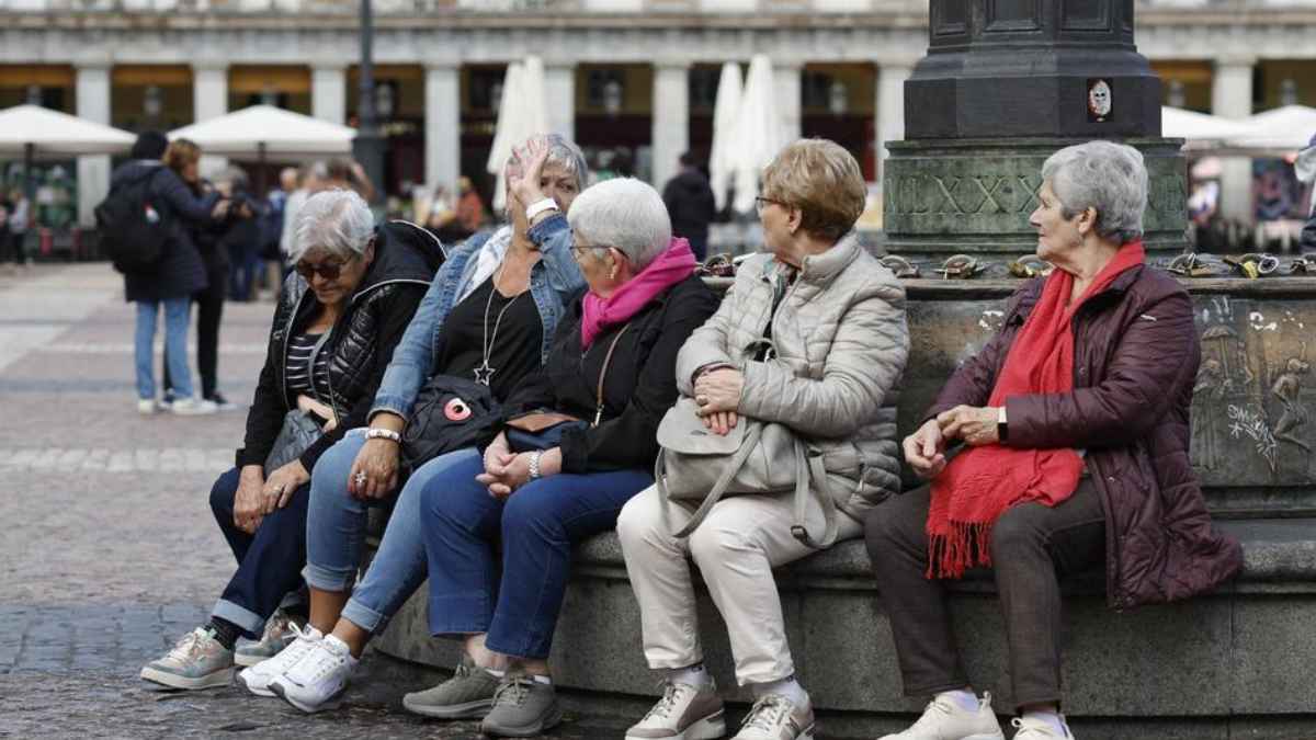 Grupo de pensionistas sentados en una plaza pendientes del cobro de la pensión de marzo de 2026
