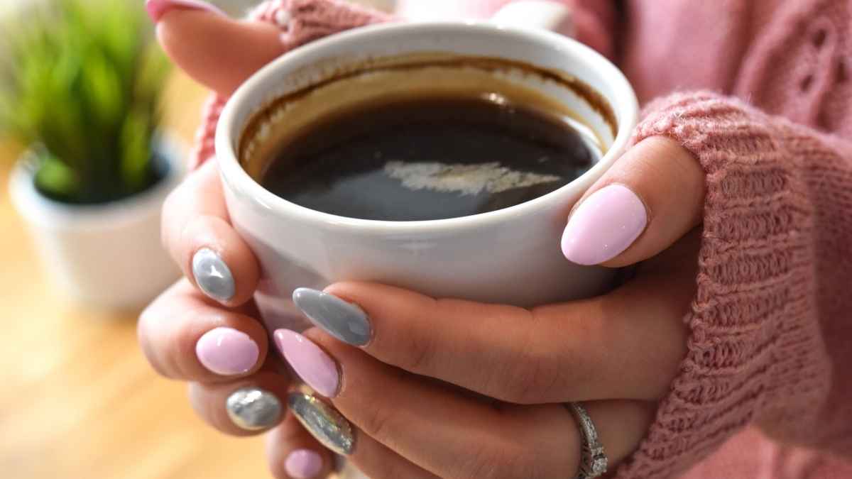 Manos sujetando una taza de café caliente, imagen para una oferta de cafetera superautomática con molinillo y vapor en El Corte Inglés.