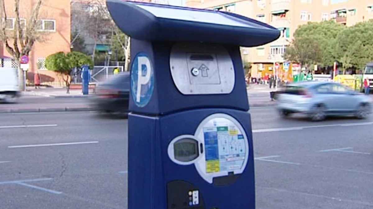 Parquímetro de la zona azul en una calle de Madrid, con coches circulando al fondo