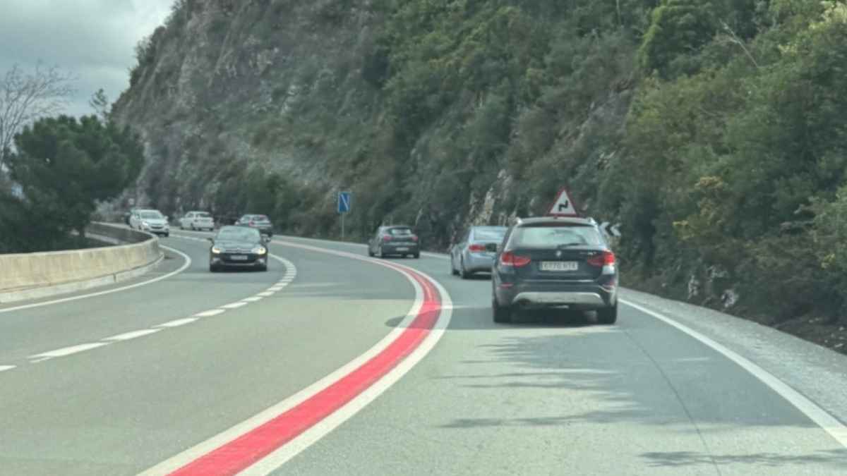 Carretera con línea roja continua entre líneas blancas, señal de la DGT en tramos peligrosos donde está prohibido adelantar